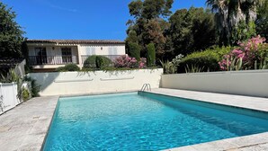 Una piscina rectangular con agua azul cristalina, rodeada por un solárium de baldosas.