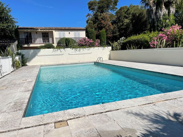 A rectangular swimming pool with clear blue water, surrounded by a tiled deck.