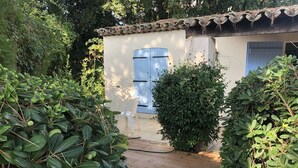Una terraza de madera que conduce a un edificio con una puerta azul y una pared blanca.