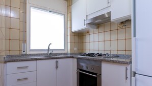 Una cocina con armarios blancos, una ventana, una estufa de acero inoxidable y un horno.