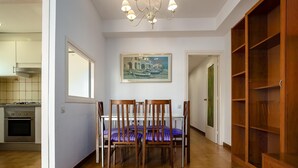Un comedor con una mesa y sillas, un cuadro en la pared y una cocina al fondo.