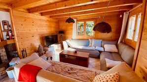 L’intérieur d’un chalet confortable, avec un canapé, un téléviseur et une cheminée.