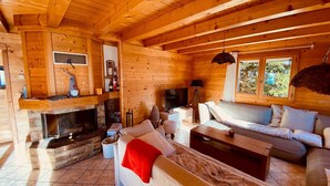 Un intérieur de chalet chaleureux avec une cheminée, des murs en bois, un canapé et un téléviseur.