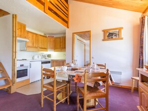 A cozy kitchen with wooden cabinets, a dining table with chairs, and a large mirror on the wall.
