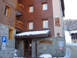 A wooden building with a stone facade, a sign reading "TETRAS LYRE," and a no parking sign.