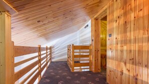 Ein Interieur aus Holz mit schrägen Decken, einer Holzbänkl und einem gemusterten Teppich.