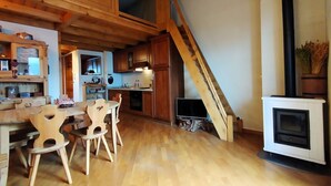 Une cuisine rustique avec des meubles en bois, un coin repas avec des chaises en bois, un escalier en bois et une cheminée.