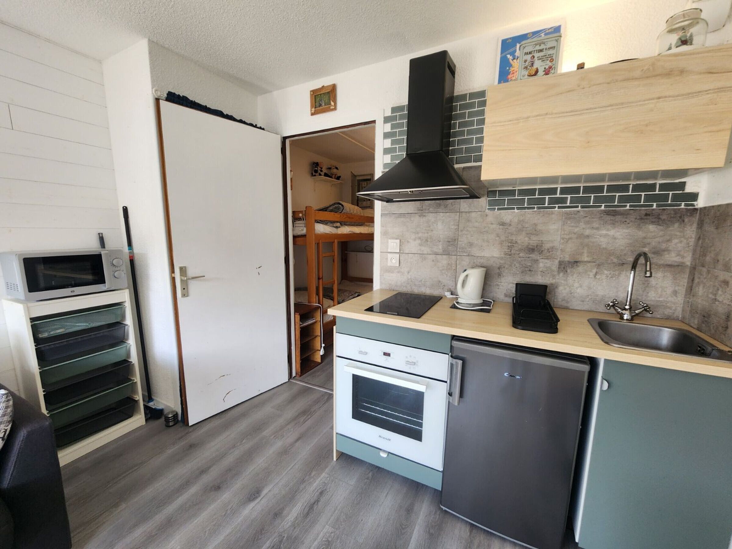 A compact kitchen with a microwave, coffee maker, sink, and a built-in oven.