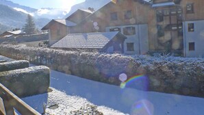 Un pueblo cubierto de nieve con edificios de madera, cielo despejado y montañas al fondo.
