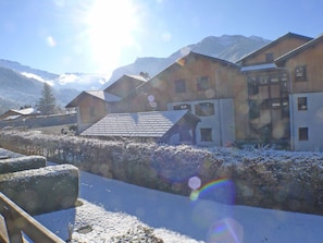 A snow-covered village with wooden buildings, a clear sky, and mountains in the background.