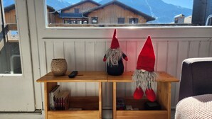 Una mesa de madera con dos figuras de gnomos, un control remoto y una estantería llena de libros.