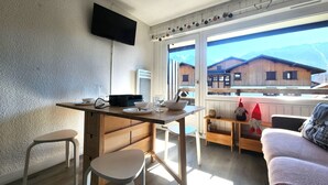 Una cocina moderna con un televisor de pantalla plana, armarios de madera y un comedor con mesa y sillas.