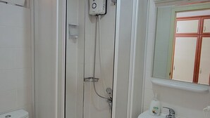 A bathroom with a glass-enclosed shower, a toilet, and a sink. - Güneş Otel (Edremit)