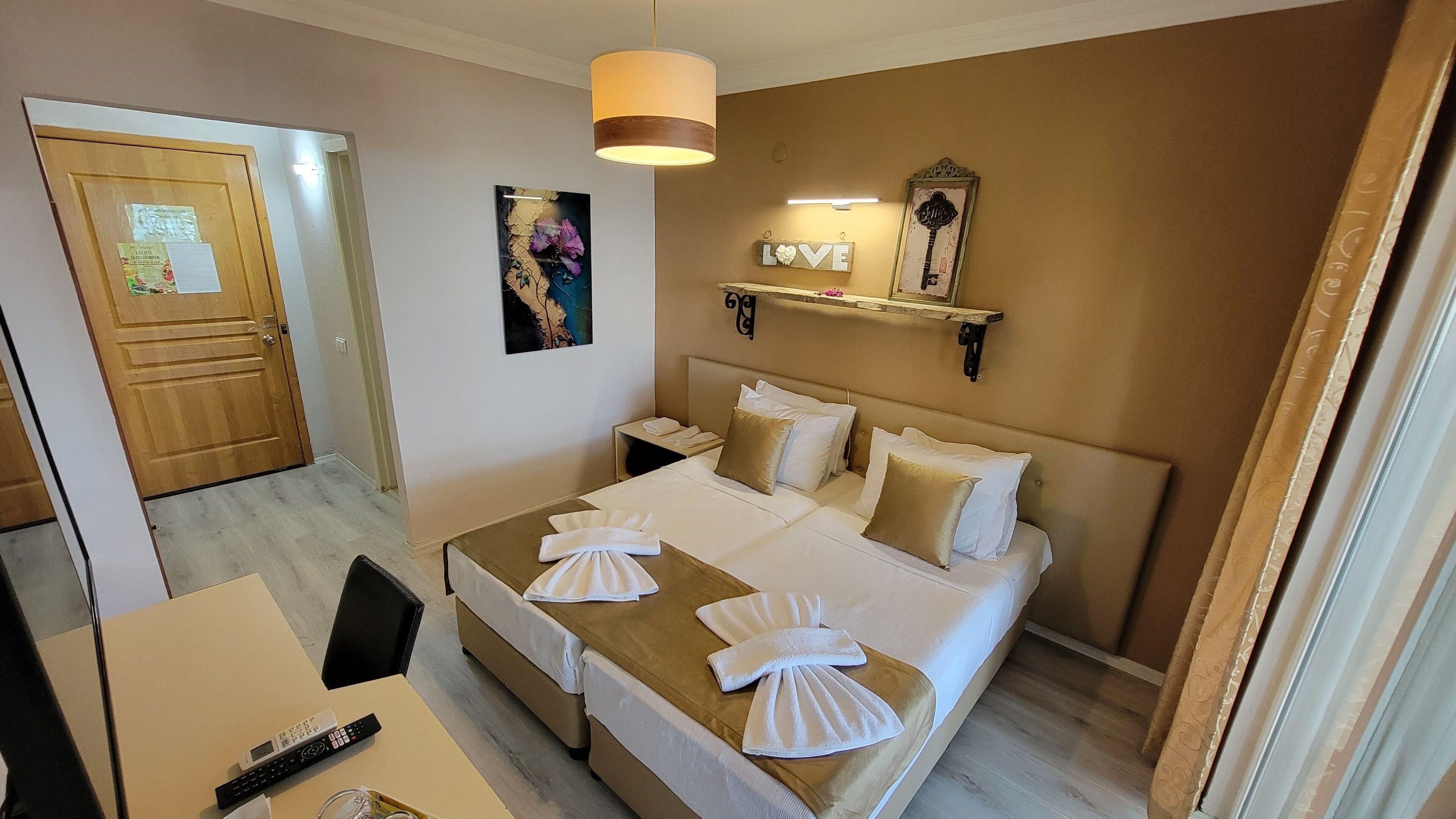 A hotel room with a bed, bedside table, and a desk with a chair.