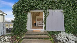 A house with a covered entrance, steps leading up to it, and a small garden area with a white shrub. - Villa in French Chateau Estate in Napa Valley (Calistoga)
