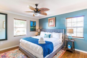 A bedroom with a bed, a ceiling fan, a nightstand, a lamp, and artwork on the walls. - The Retreat - Fast Wi-Fi - Heart of Mount Dora (Mount Dora)