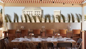 A restaurant with a checkered roof, outdoor seating, and a view of a domed building in the background. - Ergon Bakehouse Athens (Athens)