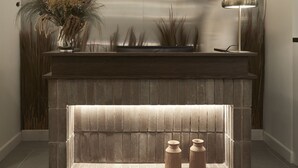 A reception area with a modern fireplace, a vase with dried plants, and a standing lamp. - Ergon Bakehouse Athens (Athens)