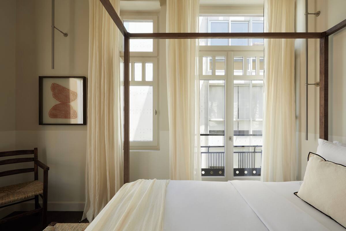 Un dormitorio con una cama con dosel, un banco de madera y un cuadro en la pared.