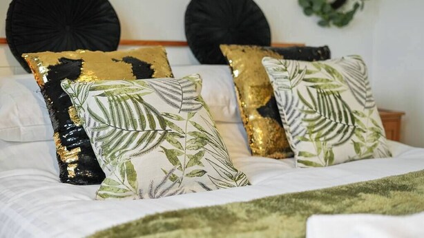 A bed with decorative pillows and a green throw blanket. - Garden Retreat w/ Free Parking & Village Access (Messingham)
