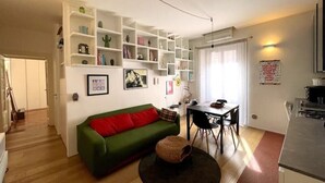 A living room with a green sofa, a dining table with chairs, and a kitchen area. - Casa d'Artista - Navigli|Tortona  (Milano)