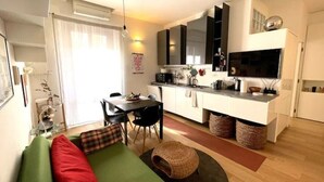 A compact living space with a sofa, a dining table, and a kitchenette. - Casa d'Artista - Navigli|Tortona  (Milano)