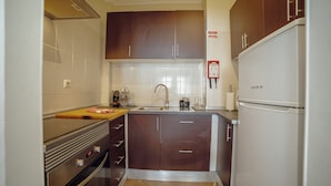 A kitchen with dark brown cabinets, a stainless steel oven, a white refrigerator, and a tiled backsplash. - Alegria Flat City Center by Vacationy (Porto)
