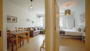 A modern, well-lit living room with a dining area, a sofa, and a bed. - Alegria Flat City Center by Vacationy (Porto)