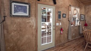 A rustic room with wooden walls, a door with glass panels, a fire extinguisher, and a chair. - Sandoval in the Historic Upper Canyon (Ruidoso)