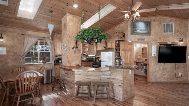 A spacious kitchen with wooden cabinets, a central island, and a ceiling fan. - Sandoval in the Historic Upper Canyon (Ruidoso)