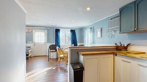 A compact kitchen with wooden countertops, a sink, and a window with blue curtains. - Gull's Nest by Bayley Vacation Rentals (Old Orchard Beach)
