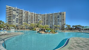 A large hotel with multiple balconies and a swimming pool with a landscaped island. - Tower 2-1002 Edgewater Beach Resort-Sleeps 8! (Panama City Beach)