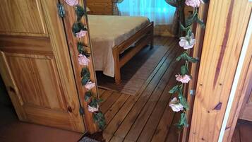 A wooden interior with a bed, curtains, and a floral decoration.