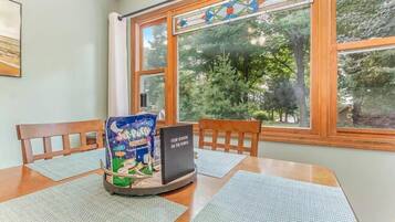 Un coin repas avec une table, des chaises, un paquet de chips et un livre intitulé « Quatre saisons sur le terrain de bowling-green ».