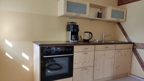 A kitchen with wooden cabinets, a built-in oven, a coffee maker, and a kettle. - Im Herzen der Sächsischen Schweiz- Fewo Bloßstock für Max. 5 Personen (Sebnitz)