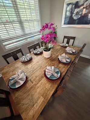A dining table set with plates, napkins, and a vase of flowers.
