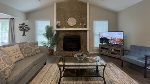 A living room with a stone fireplace, a television, a sofa, and a coffee table. - 2 King Suites Hot Tub Fire Pit Air Hockey 2 (North Charleston)