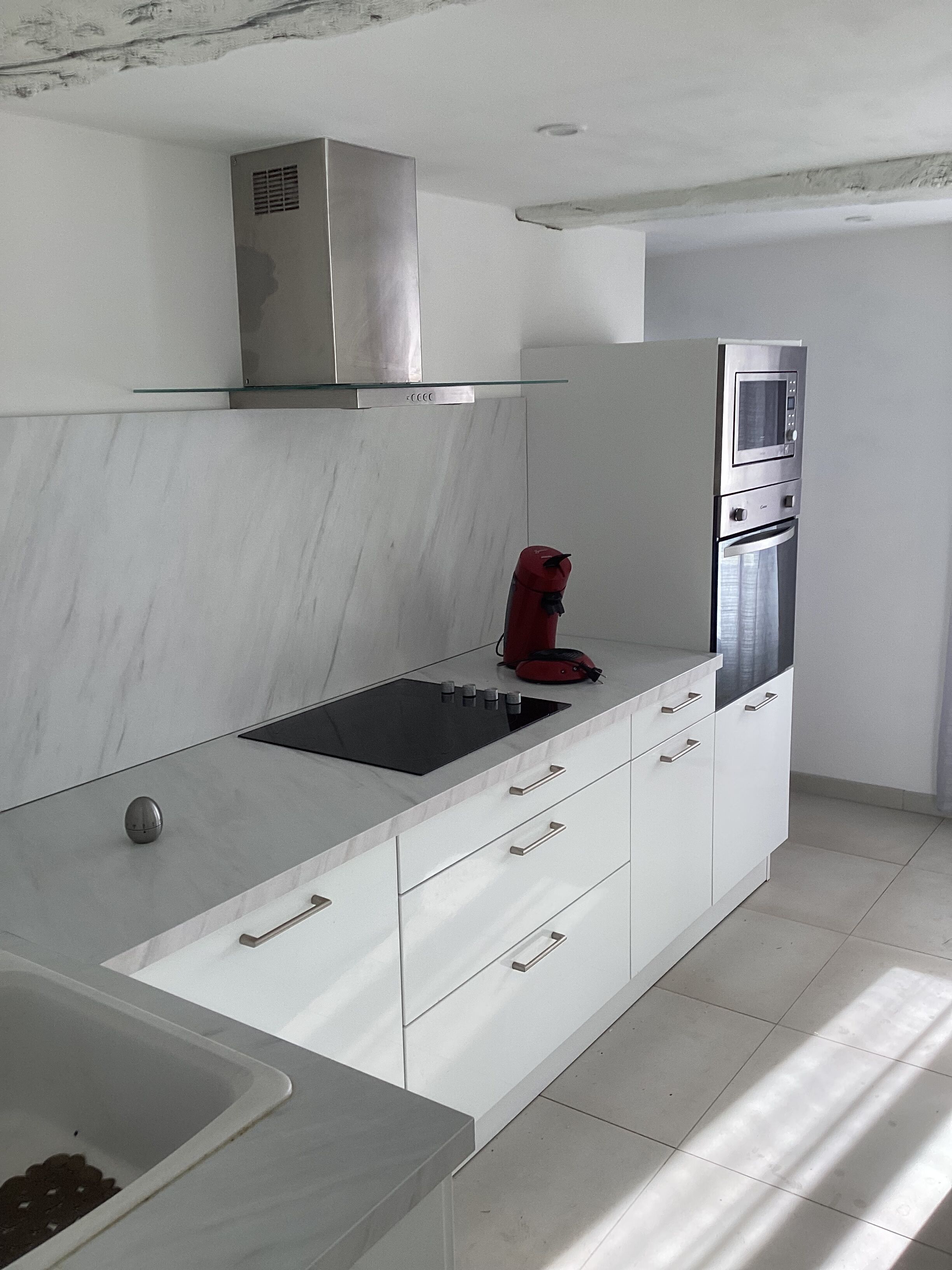 Uma cozinha moderna com exaustor de aço inoxidável, forno embutido e fogão por indução preto.