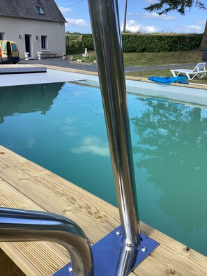 A swimming pool with a wooden deck and metal railings. - Renovated country house, quiet location, private heated pool  (Caumont-sur-Aure)