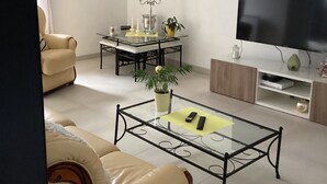 Una sala de estar con sofá, mesa de centro, televisor y un elemento decorativo en la pared.