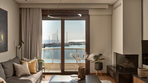 A modern living room with a sofa, coffee table, and TV. A large window offers a view of a marina. - Monopolio Waterfront Apartment (Zakynthos)