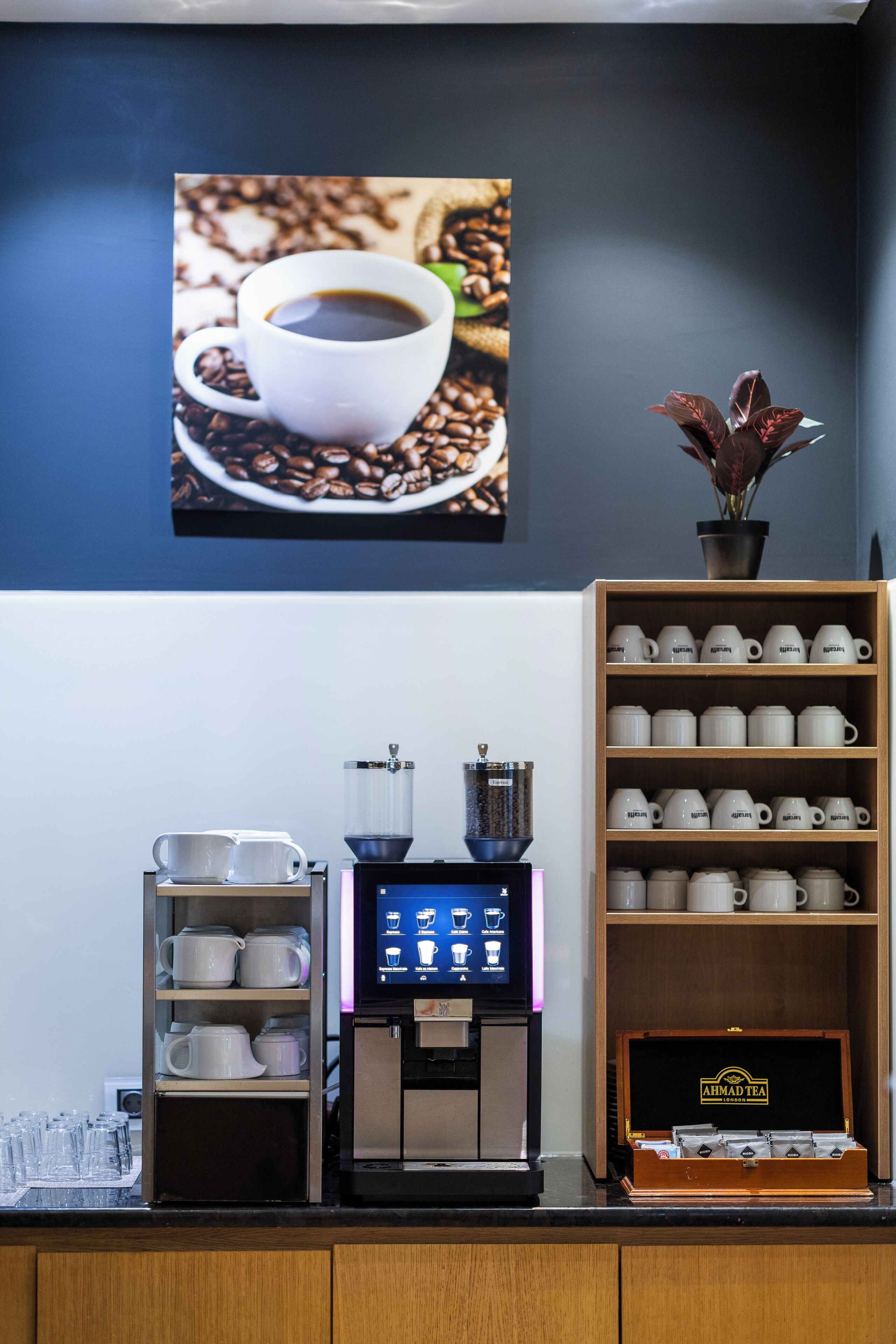 A coffee station with a coffee machine, cups, and a display of coffee beans.