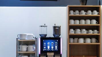 A coffee station with a coffee machine, cups, and a display of coffee beans.