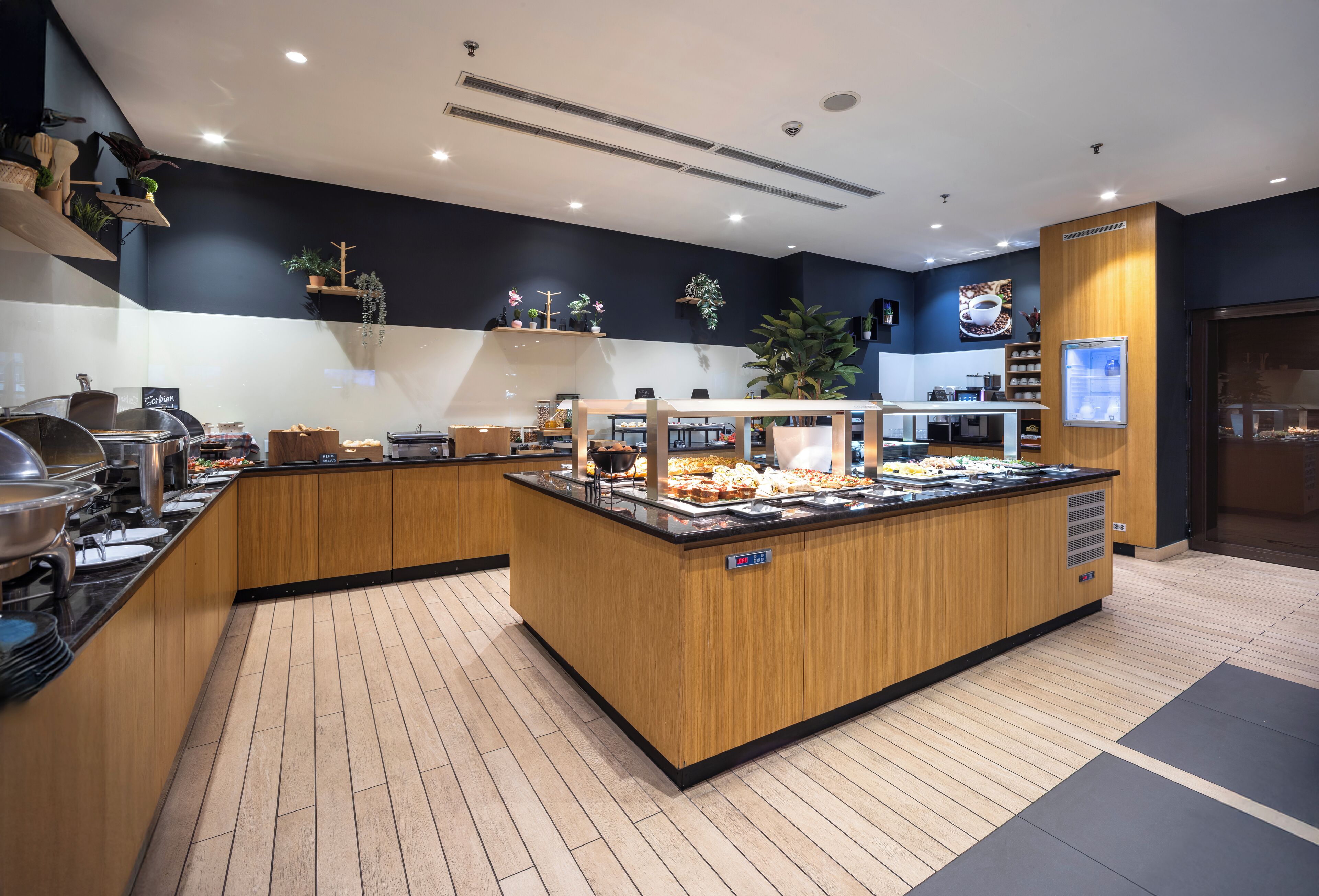 A buffet area with wooden counters, a variety of food items, and a sign indicating 'Breakfast'.