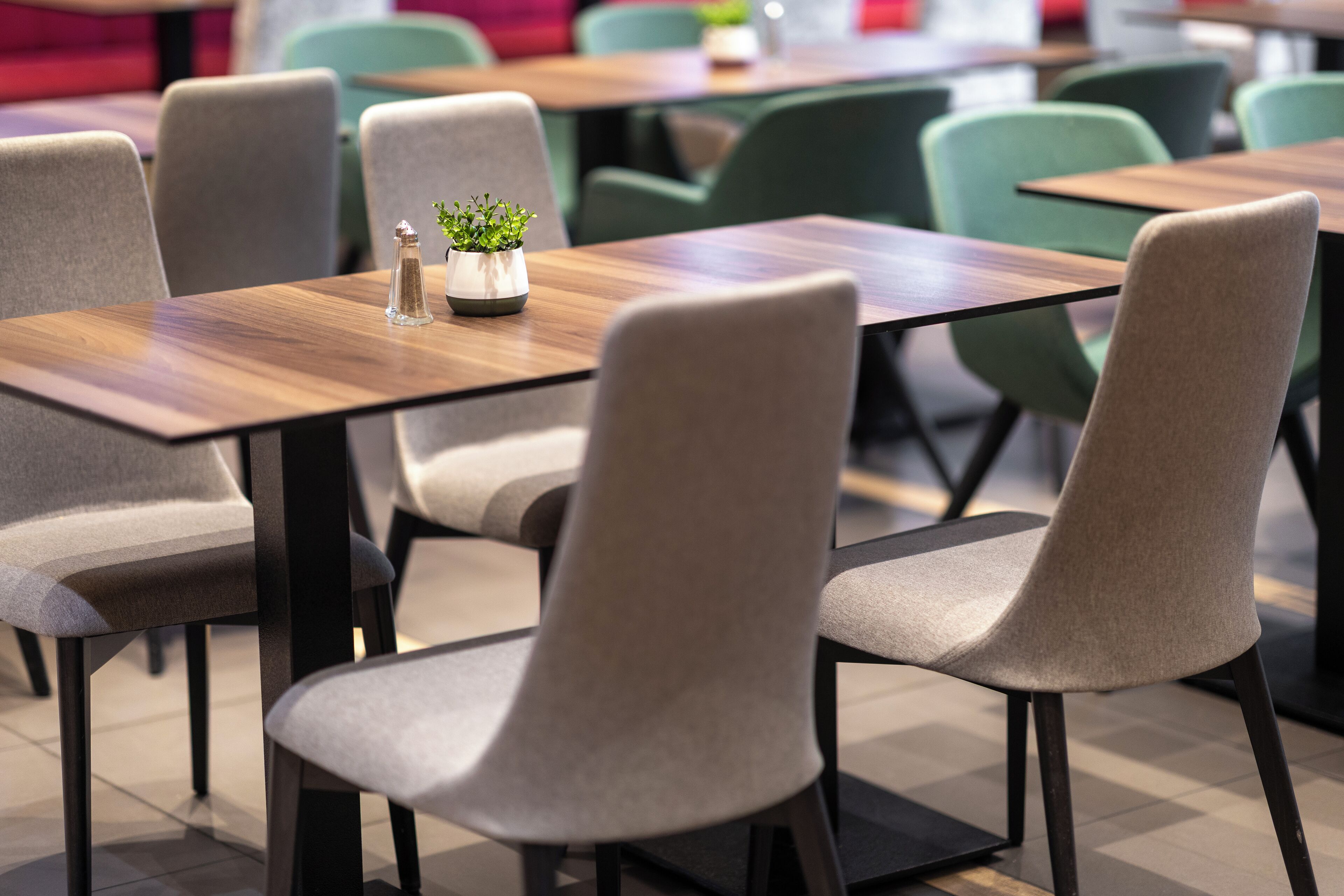Un comedor moderno con mesas de madera y sillas tapizadas de gris.