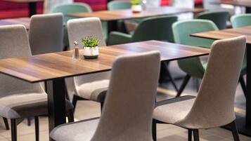 Un comedor moderno con mesas de madera y sillas tapizadas de gris.