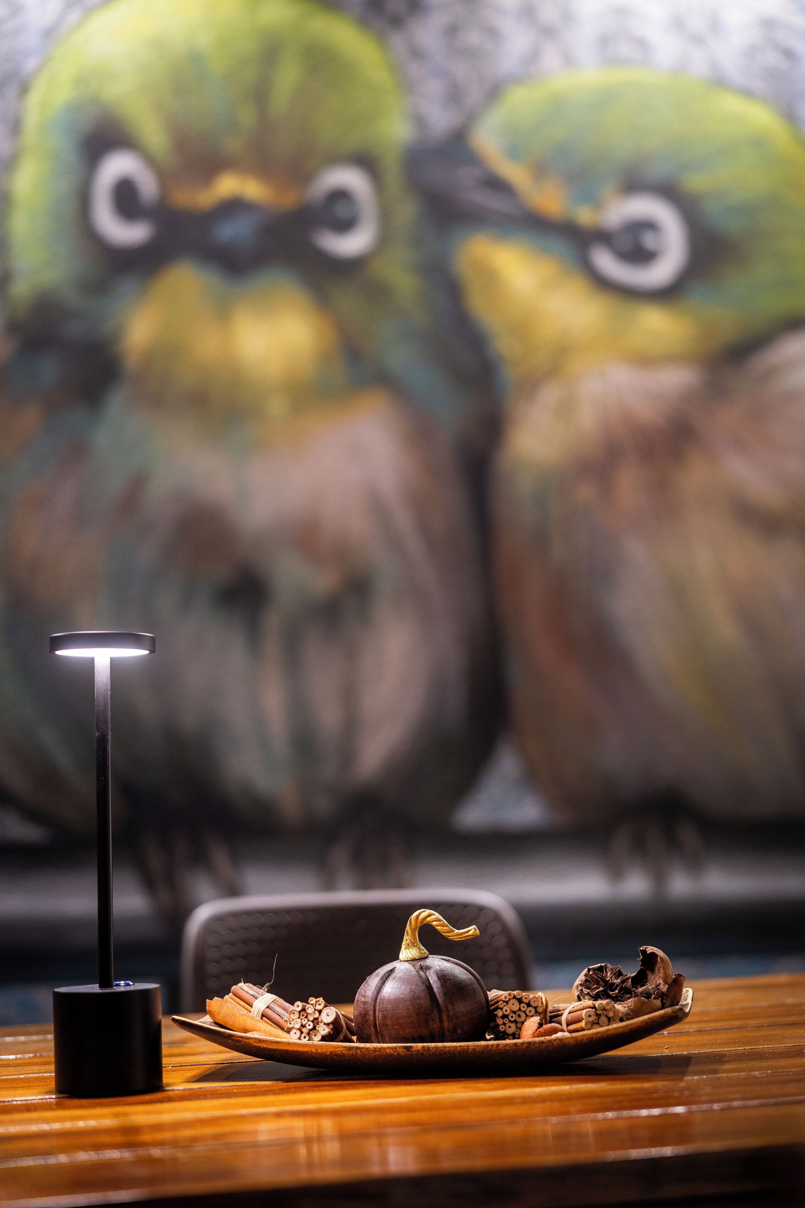 A table with a pumpkin and cinnamon sticks, a decorative plate, and a modern floor lamp.