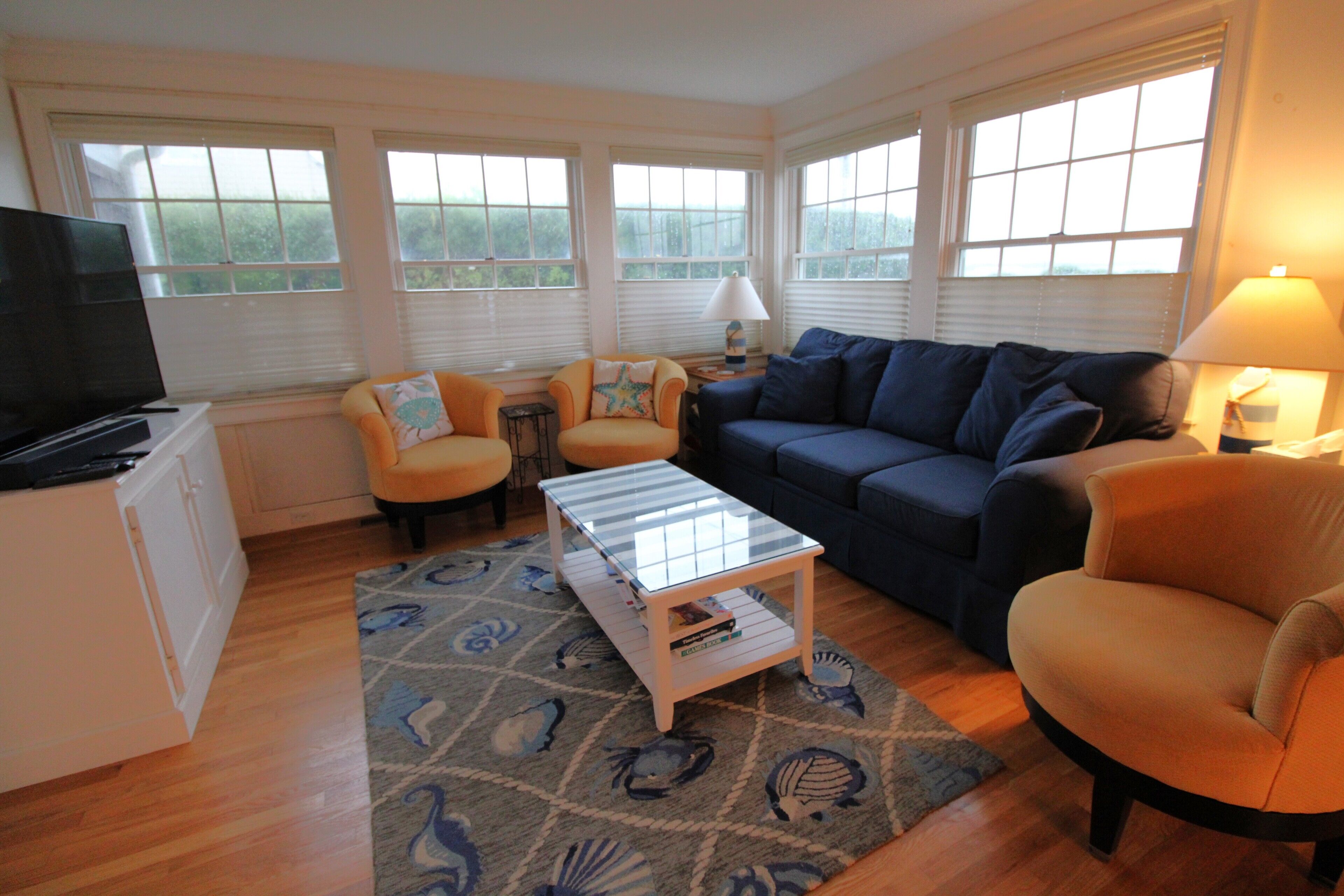 A living room with a sofa, armchairs, a coffee table, and a TV.