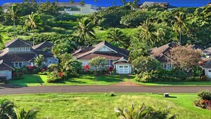 A residential area with houses, lush greenery, and a view of the ocean. - Hale Milo: Charming Garden Cottage in Sunny Poipu! (Koloa)