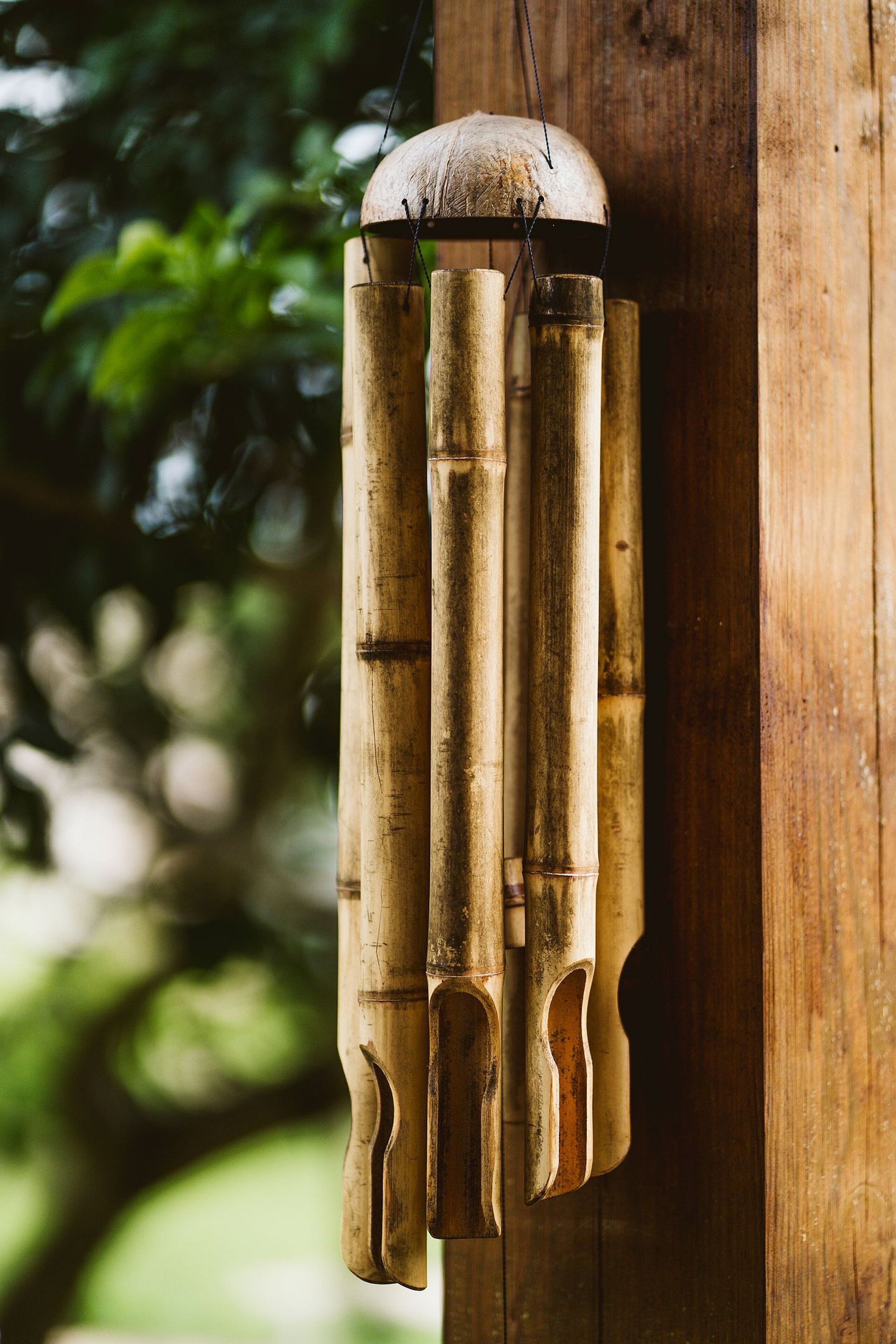 A bamboo wind chime hanging on a wooden post.